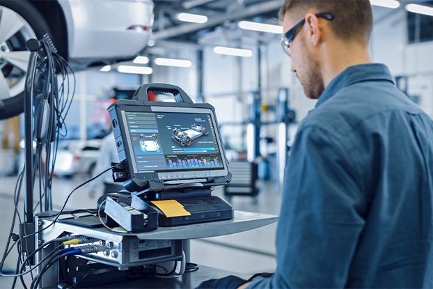  Automotive Digitalisierung: Beitragsbild eines Automotive Branchenportals: Ingenieur in der Fahrzeugbranche führt Diagnosen und Optimierungen mit Tablet und Sensoren im Kontext von Digitalisierung und Glasfasernetzwerken durch. Menschen in der Automobilindustrie arbeiten an digitalen QM-Systemen für Fahrzeuge mit Diagnose- und Fernwartungsfunktionen