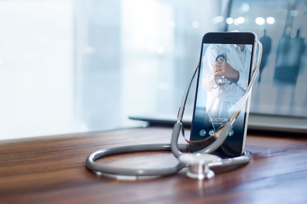 Das Beitragsbild des Branchenportals für digitale Healthcare Kommunikationstechnologien zeigt ein Mobiltelefon mit dem Foto eines Arztes. Das Stethoskop hängt über dem Mobiltelefon und bringt so die digitale Diagnose zum Ausdruck.