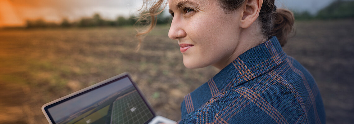 Frau mit Laptop auf einem Feld