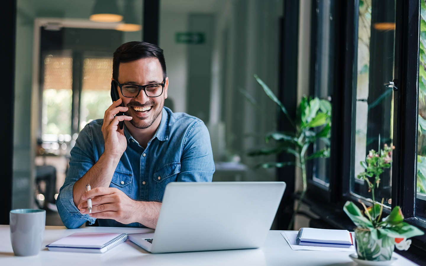 Mann telefoniert glücklich im Homeoffice nach Wechsel zur Cloud-Telefonanlage